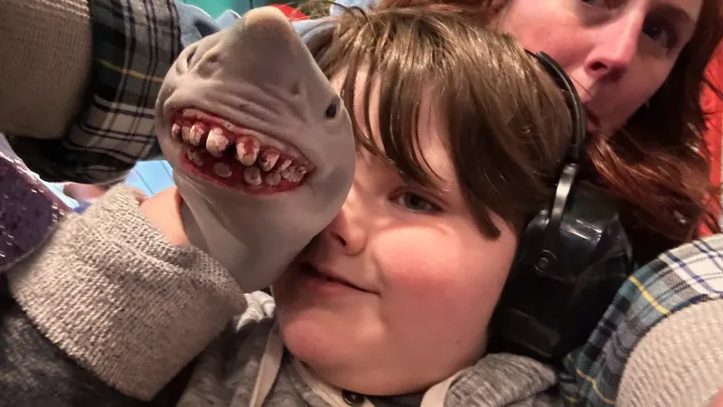 autistic child with his shark puppet and mom