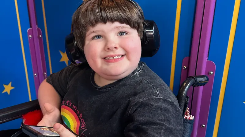 child wearing noise canceling headphones sitting in a wheelchair