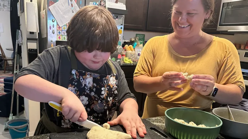 little boy making pizza muffins with his occupational therapist