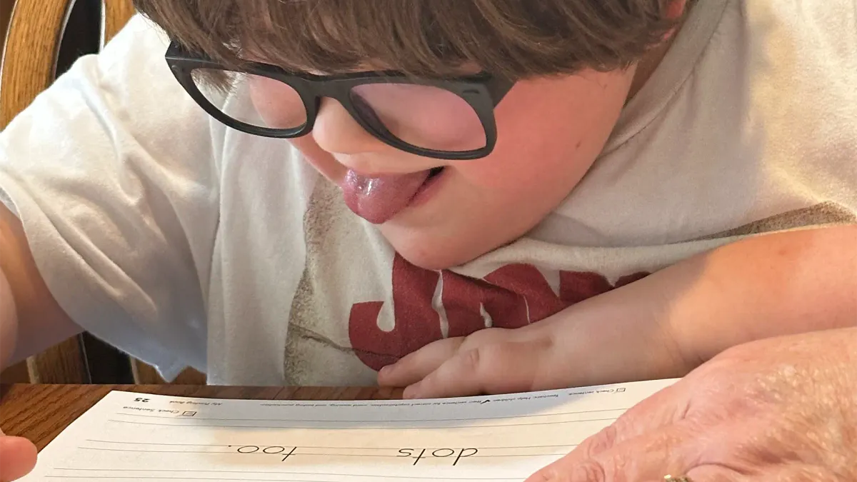 young autistic boy working on schoolwork with his tutor